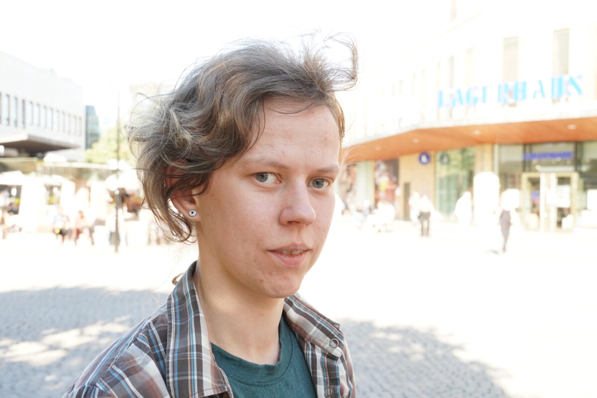 Mari med litet leende, en solig dag på torget i Farsta centrum. En sommarbris fläktar i håret.